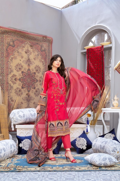Schönes junges Mädchen winkt Dupatta in rotem Desi-Kleid für Indoor-Mode-Shooting