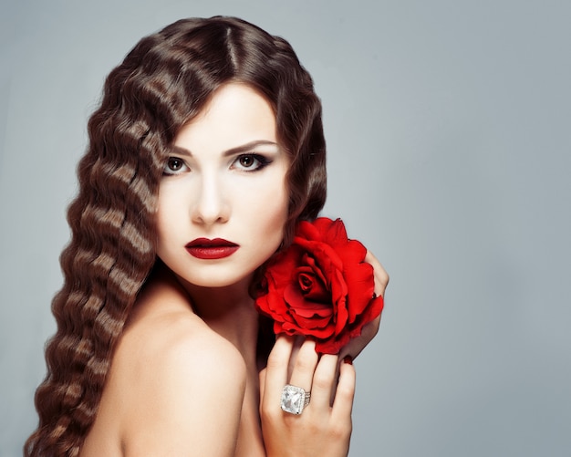 Schönes junges Modell mit den roten Lippen und Rotrose