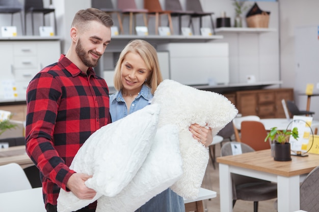 Schönes junges Paar, das für Bettwäsche zusammen zu Hause Warenladen einkauft