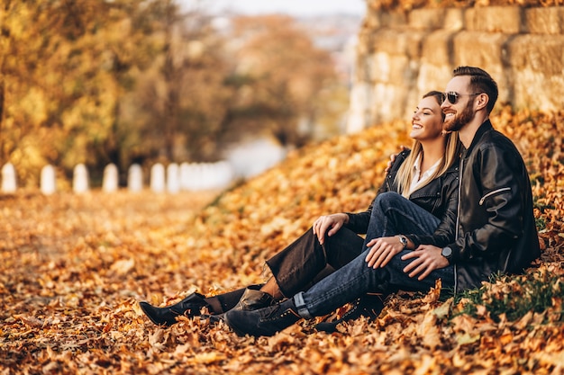 Schönes junges Paar, das im Herbstpark an einem sonnigen Tag geht