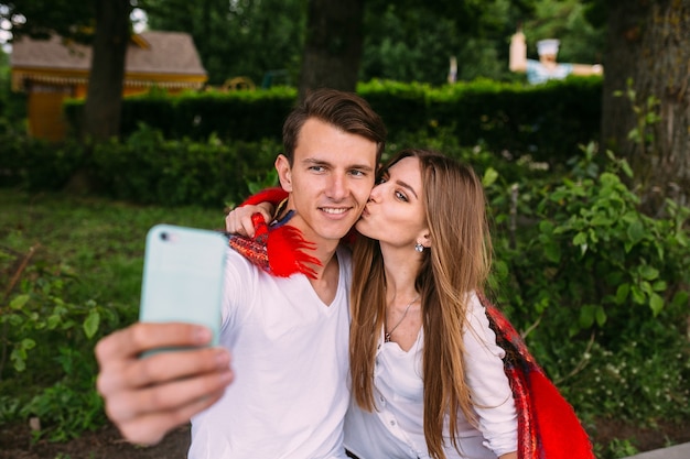 Schönes junges Paar, das sich im Park entspannt und Selfie macht