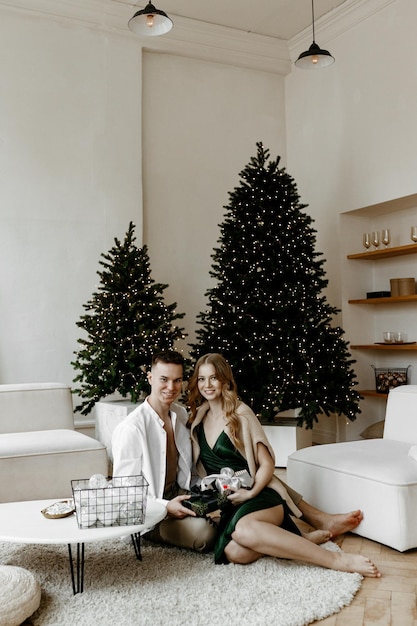 Schönes junges Paar, das zu Hause in einem hellen Wohnzimmer Weihnachtsgeschenke austauscht