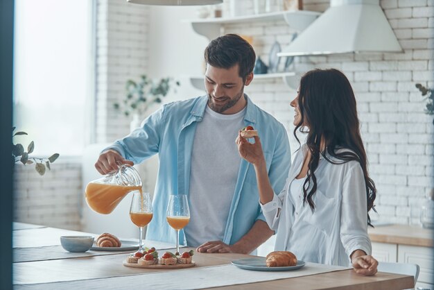 Schönes junges Paar, das zusammen Frühstück zubereitet, während es Zeit in der heimischen Küche verbringt