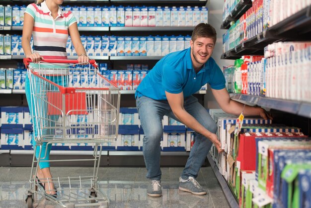 Schönes junges Paar Einkaufen für Milch und Käse In Produzieren Abteilung eines Supermarktes Supermarkt Flache Tiefe des Feldes