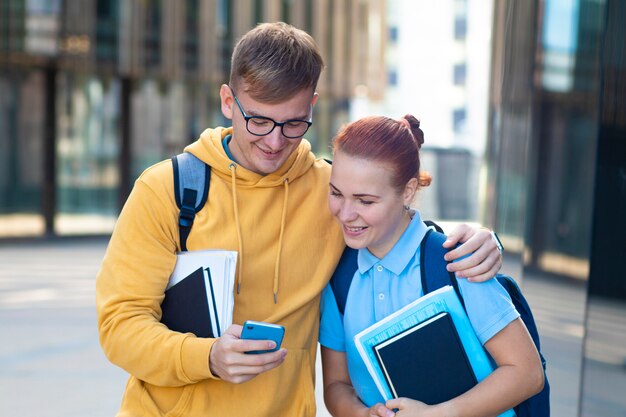 Schönes junges Paar, glückliche Studenten mit Büchern, Lehrbücher, die draußen zusammen stehen.