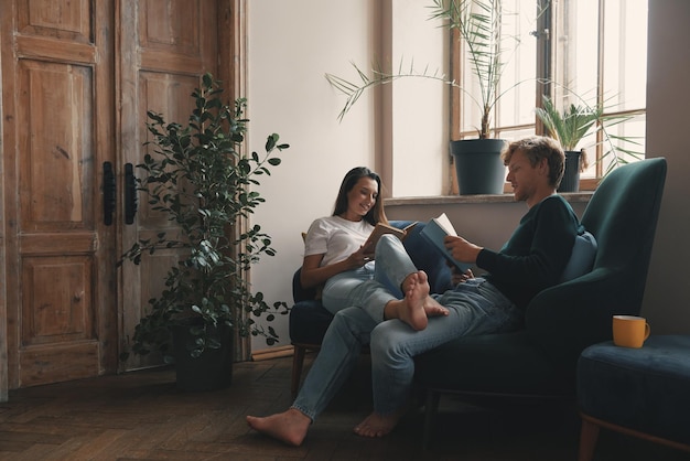 Schönes junges Paar liest Bücher, während sie sich zu Hause zusammen entspannen