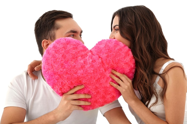 Schönes junges Paar mit pelzigem Kissen in Herzform auf hellem Hintergrund