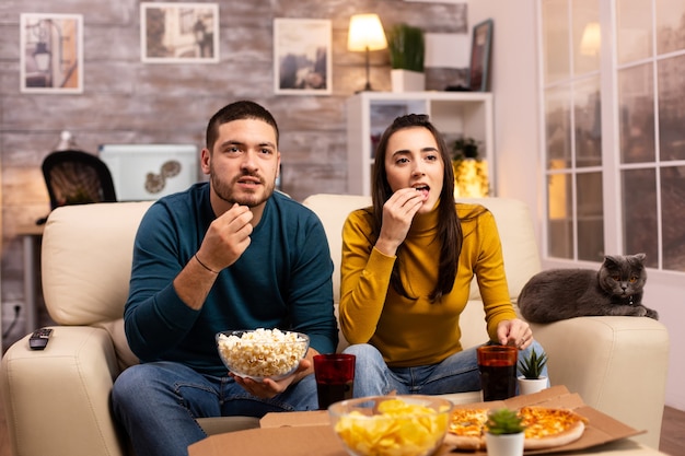 Schönes junges Paar vor dem Fernseher und Essen zum Mitnehmen im Wohnzimmer?