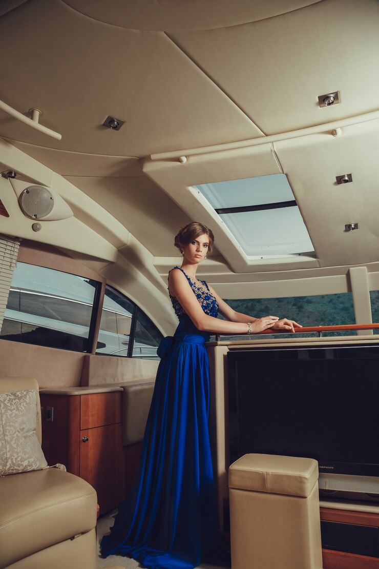 Schönes junges sexy Mädchen in einem Kleid und Make-up, Sommerreise auf einer Yacht mit weißen Segeln auf dem Meer oder Ozean