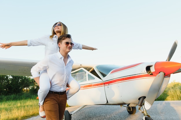 Schönes junges stilvolles Paar in der offiziellen Kleidung, die im Privatflugzeug steht