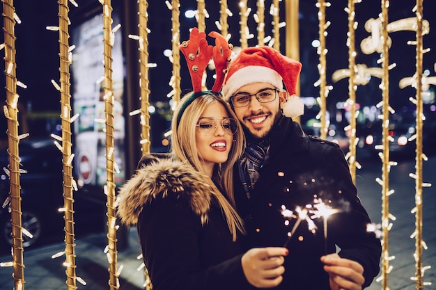 Schönes junges verliebtes paar, das weihnachts- oder neujahrsnacht auf einer stadtstraße genießt.