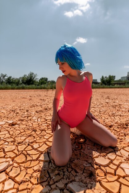 Schönes junges vorbildliches Mädchen mit kurzen blauen Haaren in der Wüstenaufstellung