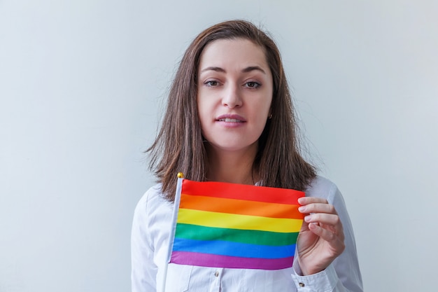 Schönes kaukasisches lesbisches Mädchen mit LGBT-Regenbogenfahne lokalisiert auf Weiß