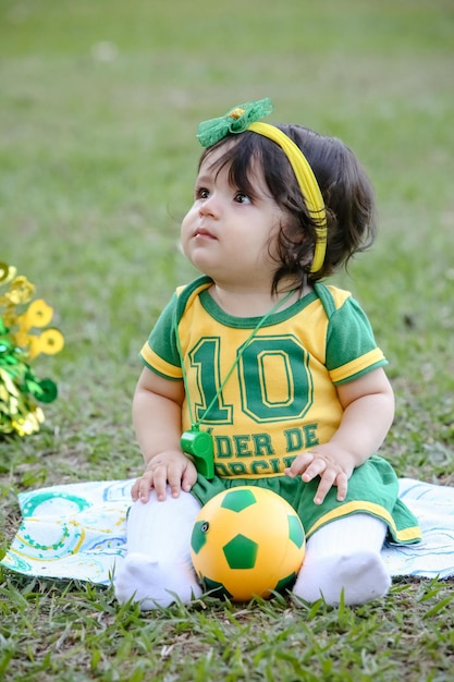 Schönes Kind der brasilianischen Fußballmannschaft in einem grün und gelb gekleideten Park