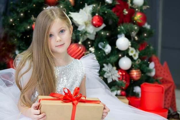 Schönes Kind mit einem Weihnachtsgeschenk Dressing up Mädchen am Neujahrsbaum