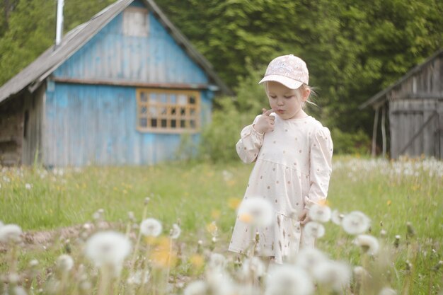 Schönes Kind mit Löwenzahnblumen im Park im Sommer Glückliches Kind, das Spaß im Freien hat