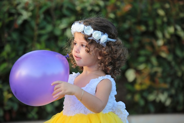 Schönes Kindermädchen, das gelbes Kleid in einem Feldhauspark im Freien Sommerhintergrund trägt