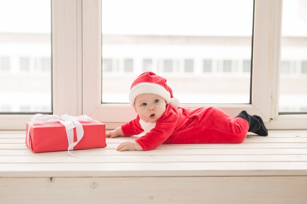 Schönes kleines Baby feiert Weihnachten. Neujahrsfeiertage. Baby in einem Weihnachtskostüm und in Weihnachtsmütze.