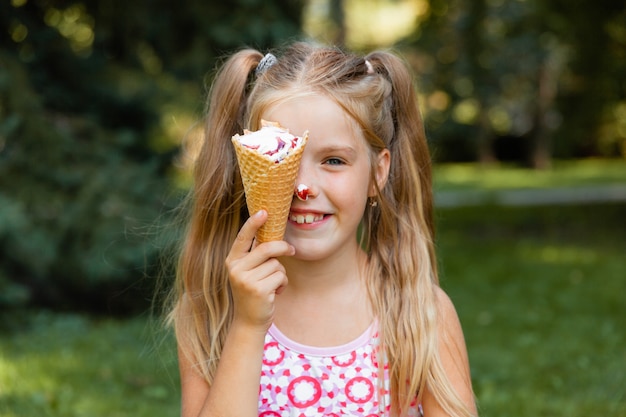 Schönes kleines blondes Mädchen, das im Sommer im Park Eis isst. fröhliches Mädchen mit Eis.