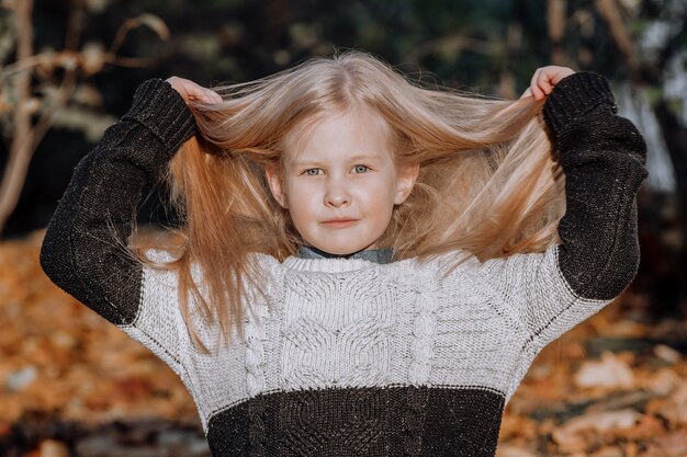 Schönes kleines blondes Mädchen im Park im Herbst