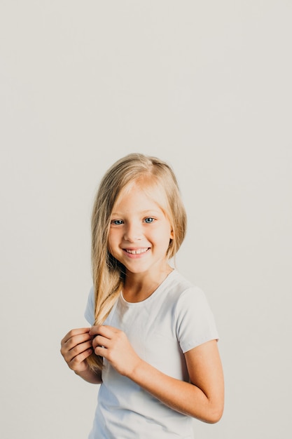 Schönes kleines blondes Mädchen in einem weißen T-Shirt