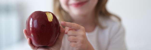 Schönes kleines lächelndes Mädchen isst roten reifen Apfel
