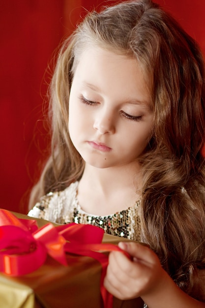 Schönes kleines Mädchen, das eine Geschenkbox öffnet. Weihnachten, Neujahr und Geburtstagsfeier.