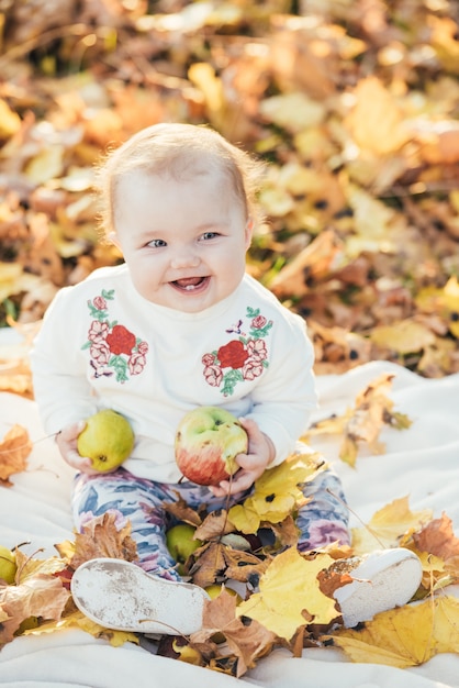 Schönes kleines Mädchen, das im Herbst auf der Natur im Park spielt