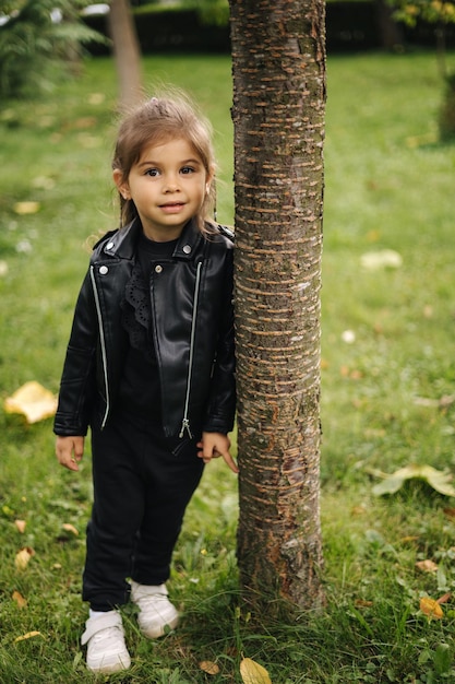 Schönes kleines Mädchen, das im Park glückliche Kinderherbststimmung im Freien spaziert