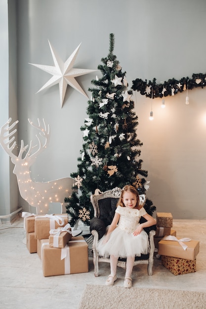 Schönes kleines Mädchen durch Weihnachtsbaum. Foto in voller Länge auf Lager