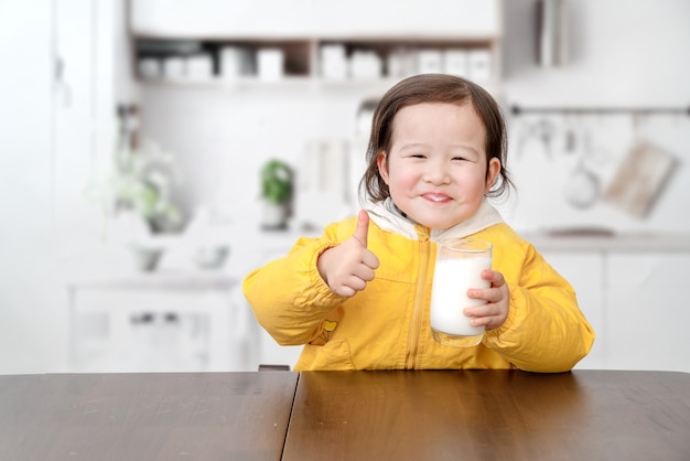 schönes kleines Mädchen frühstückt und trinkt Joghurt mit einem Löffel