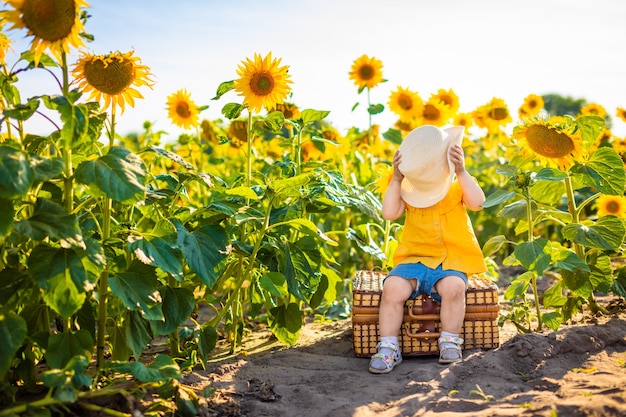 Schönes kleines Mädchen im blühenden Sonnenblumenfeld im Sommer