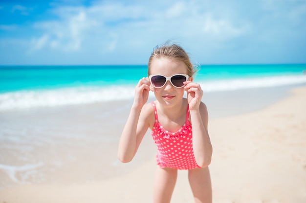 Schönes kleines Mädchen im Kleid am Strand, der Spaß hat.