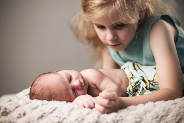 Schönes kleines Mädchen im Kleid schaut Bruder an