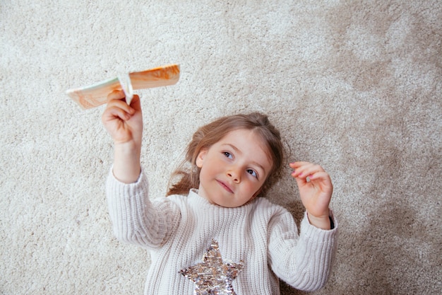 Schönes kleines Mädchen lokalisiert mit einem Papierflugzeug