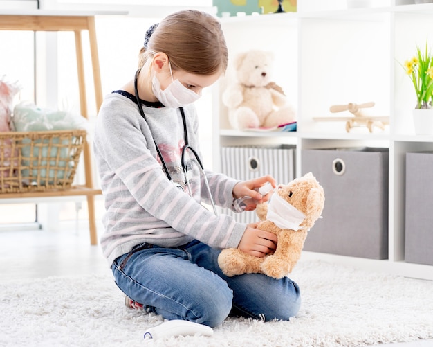 Schönes kleines Mädchen mit Desinfektionsmittel auf Teddybär