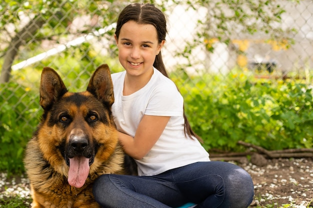 Schönes kleines Mädchen mit einem deutschen Schäferhund, der tagsüber auf dem Rasen spielt.