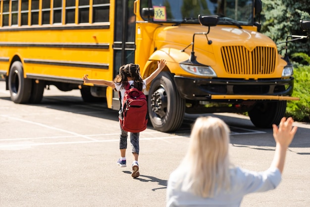 Schönes kleines Mädchen mit Mutter in der Nähe der Schule