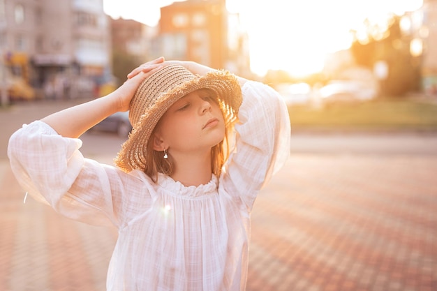 Schönes kleines Mädchen mit Sommersprossen im Gesicht Mädchen in einer weißen Bluse und mit einem Strohhut auf dem Kopf