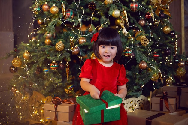 Schönes koreanisches Mädchen in einem roten Kleid öffnet eine grüne Geschenkbox