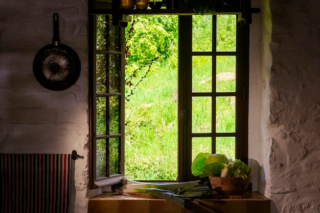Schönes Küchenholzfenster im Sommer mit Gemüse auf der Fensterbank