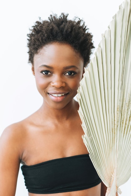 Schönes lächelndes afroamerikanisches Schönheitsmodemodell der jungen Frau mit trockenem Blatt