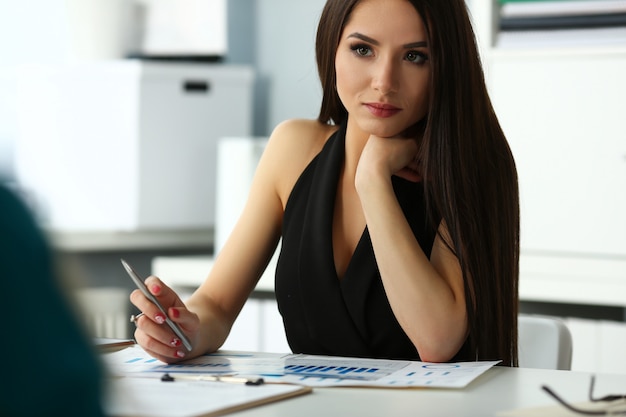 Schönes lächelndes brünettes Schreibermädchen am Arbeitsplatz