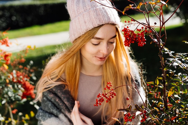 Schönes lächelndes junges Mädchen in einem rosa Hut, das an einem warmen Frühlingstag durch den Park geht