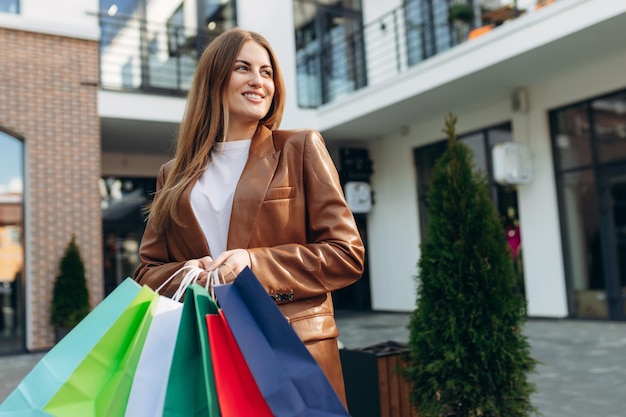 Schönes lächelndes Mädchen, das farbige Taschen hält und ihr Einkaufen genießt Shopping-Verkauf-Lifestyle-Konzept