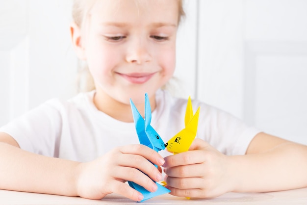 Schönes lächelndes Mädchen spielt mit Papierkaninchen