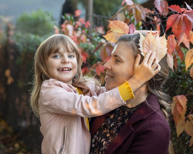 Schönes Lebensstil-Herbstsaisonfoto von Mutter und Kindtochter, die im Herbst im Park gehen.