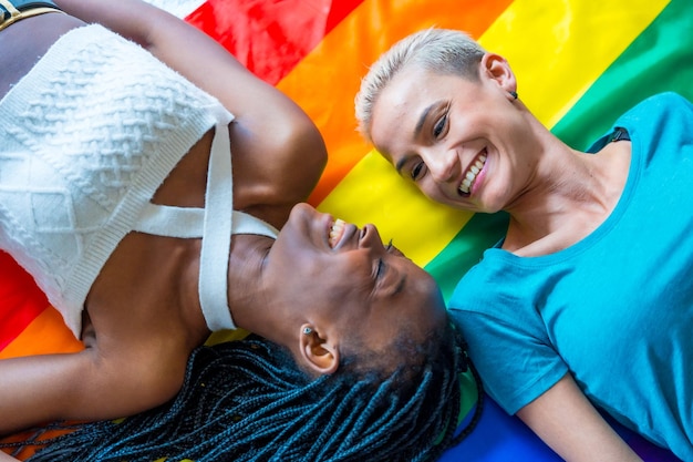 Schönes lesbisches Paar über Regenbogenfahne lgbt-Konzept romantische Pose lächelnd