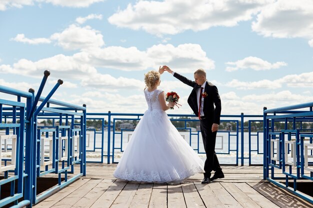 Schönes liebevolles Hochzeitspaar registriert eine Ehe und geht entlang der schönen Promenade. Glück und Liebe in den Augen von Männern und Frauen.