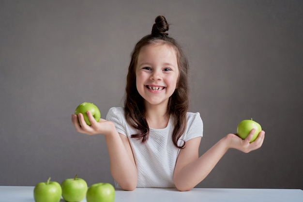 Schönes lustiges Mädchen mit grünen Äpfeln. Richtige Ernährung ist Gesundheit.